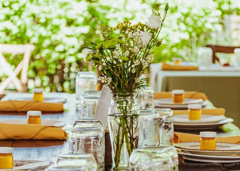 A photo of plates lined along a dinner table with flowers in the middle