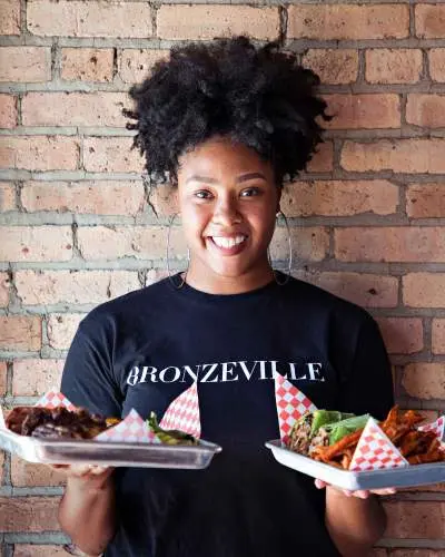 Woman holding food in front of brick wall