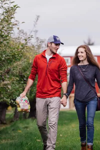 Couple walking down the Jonamac Orchard.