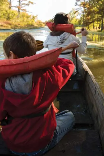 A family with lifejackets on canoeing down a river