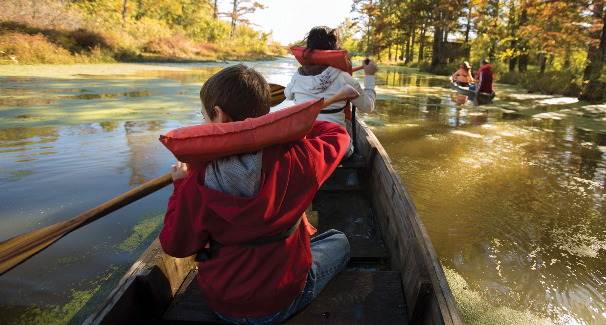 A family with lifejackets on canoeing down a river