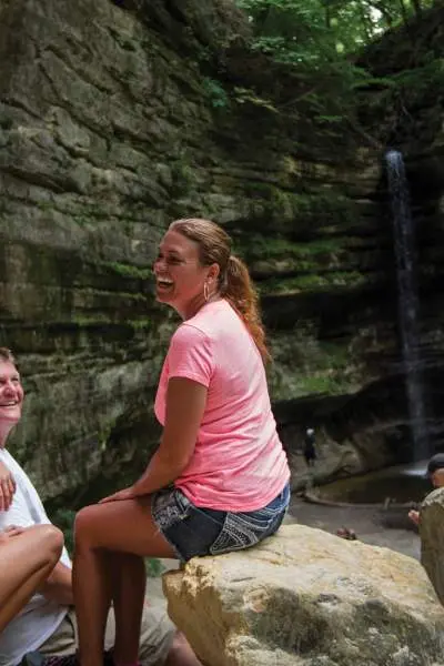 A family of four sitting down for a rest on rocks in front of a waterfall