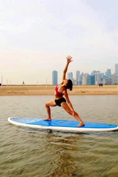 Lady stretching on paddle board on lake