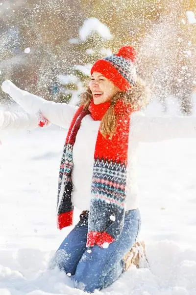 A mother with her child dressed warmly for the weather and throwing snow in the air