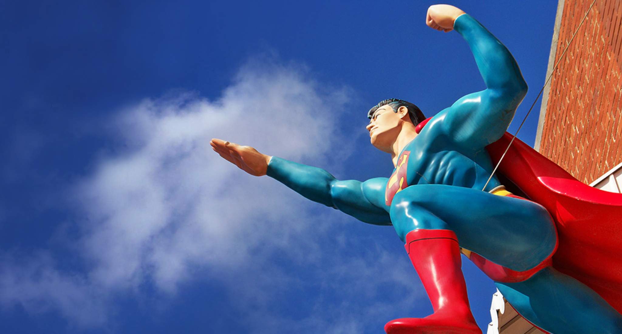 A statue of superman against a blue sky